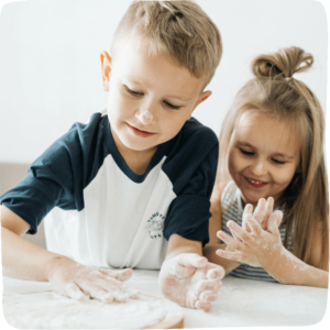 brother and sister patting flour on a counter together