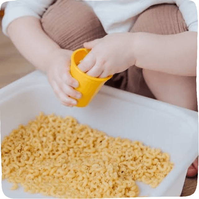 little hands in a bin of dry macaroni