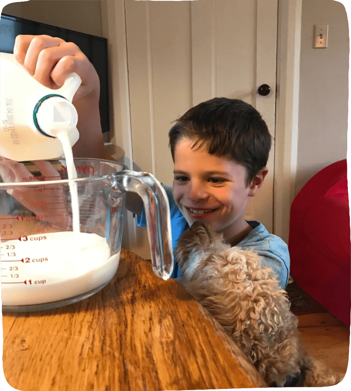 Child pours milk into a large measuring cup