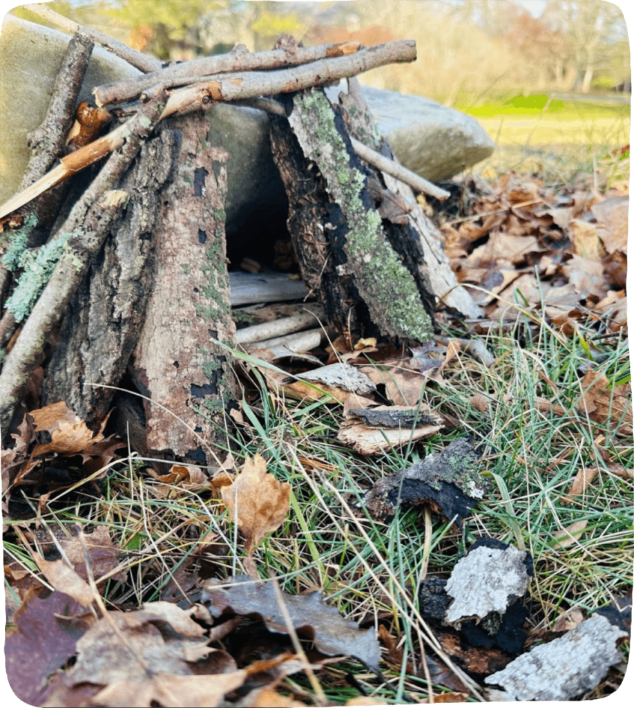 Image of a summer nature activity for kids: A small fairy house made from sticks, stones, and bark.