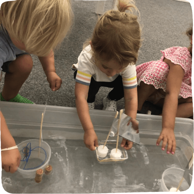 Image of children engaging in fun STEM Activities: Sailing their homemade boats in a tub of water. 