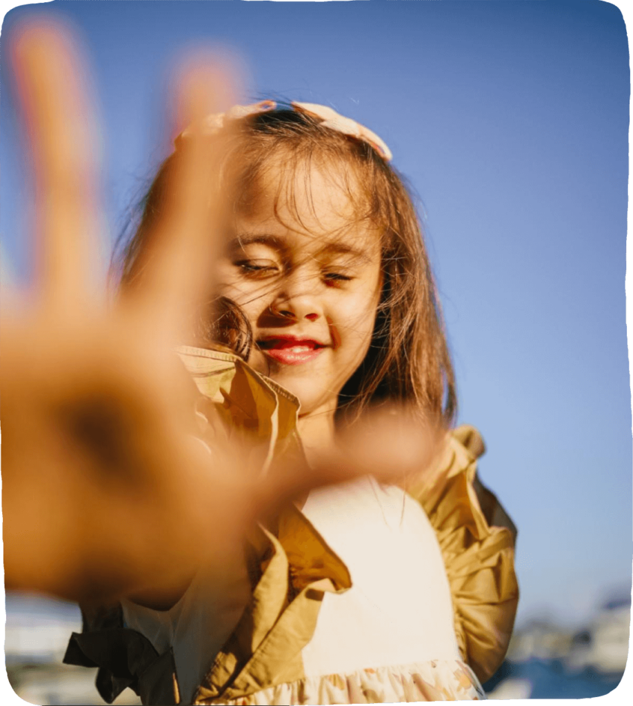 Image of a young child reaching her arm and hand out in front of her with palm and fingers stretched. She is facing the camera looking brave and ready to try these out these social-emotional learning ideas and breathing techniques. 