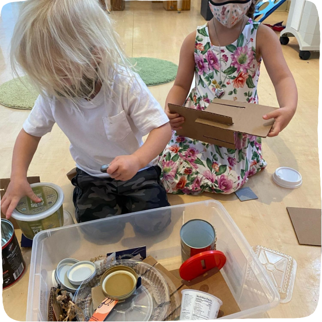 Image of children playing and experimenting with recycled parts in a bin during this fun activity to do with kids inside.