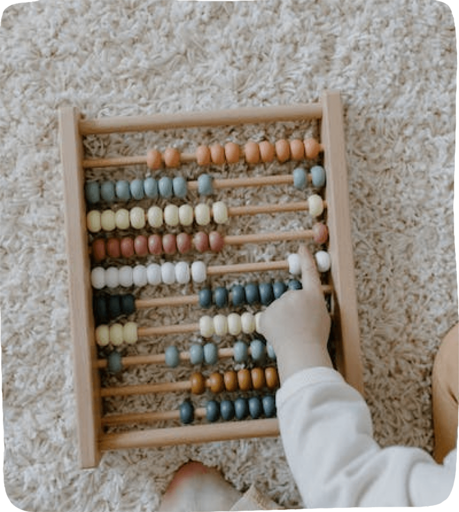 An image of a real abacus with a child's finger touching it while counting and making learning math fun.