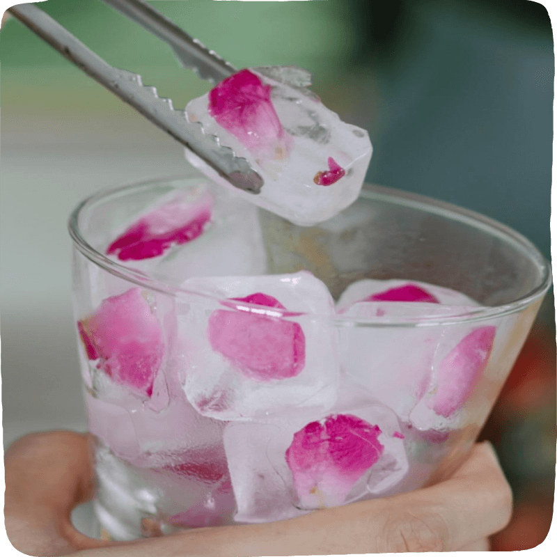 tongs grabbing an ice cube with flowers frozen into it
