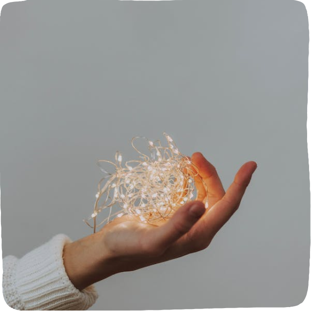 Image of a a hand holding twinkle lights - a critical material involved in the making of a DIY light table.