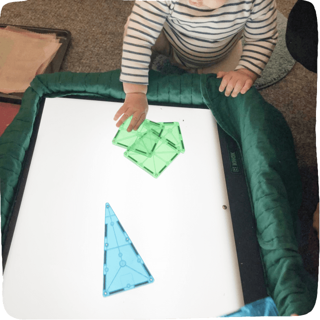 hands on a light table with magnatiles