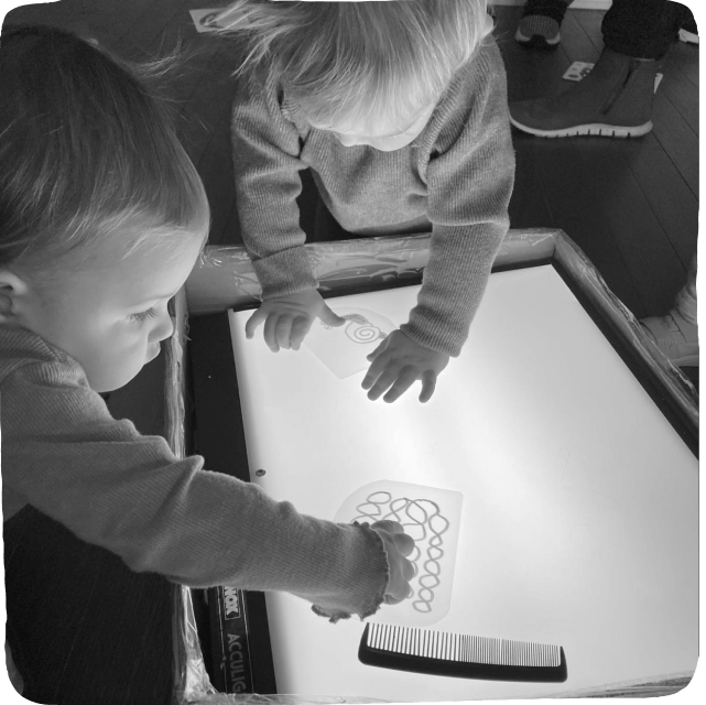babies playing at light table black and white
