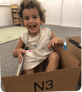 Girl sitting in a box playing.