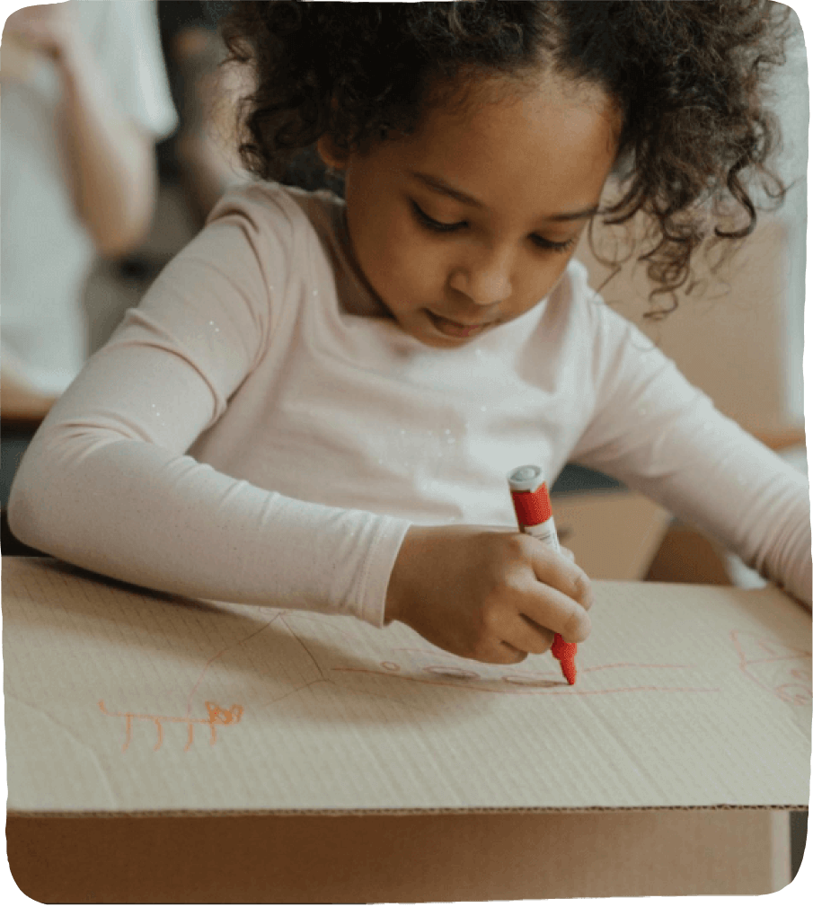 Girl drawing on cardboard box.