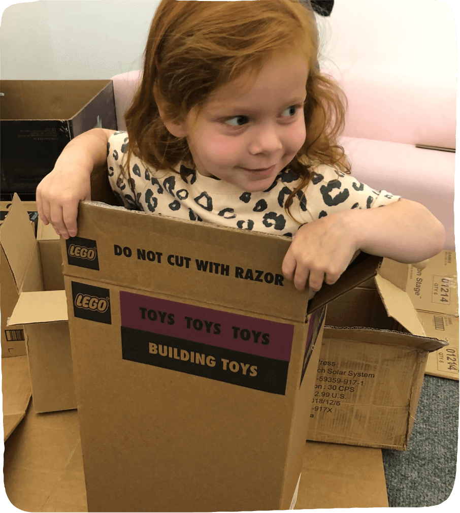 Little girl "wearing a box" to show the wide range of uses for card board boxes and the posibillites of play. 