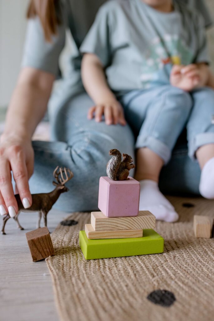 little girl and her mother playing with blocks and small plastic animals