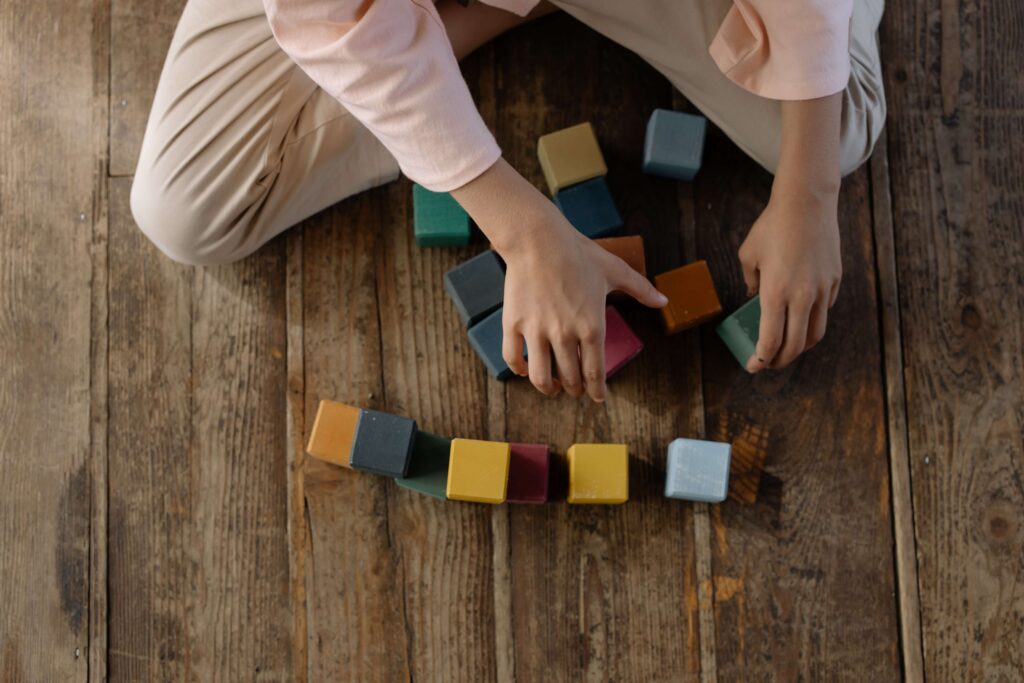 child's hand in frame lining up wooden cube shaped blocks