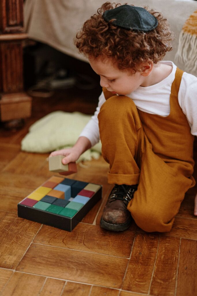 Little boy in a yarmulka and overalls playing with wooden blocks