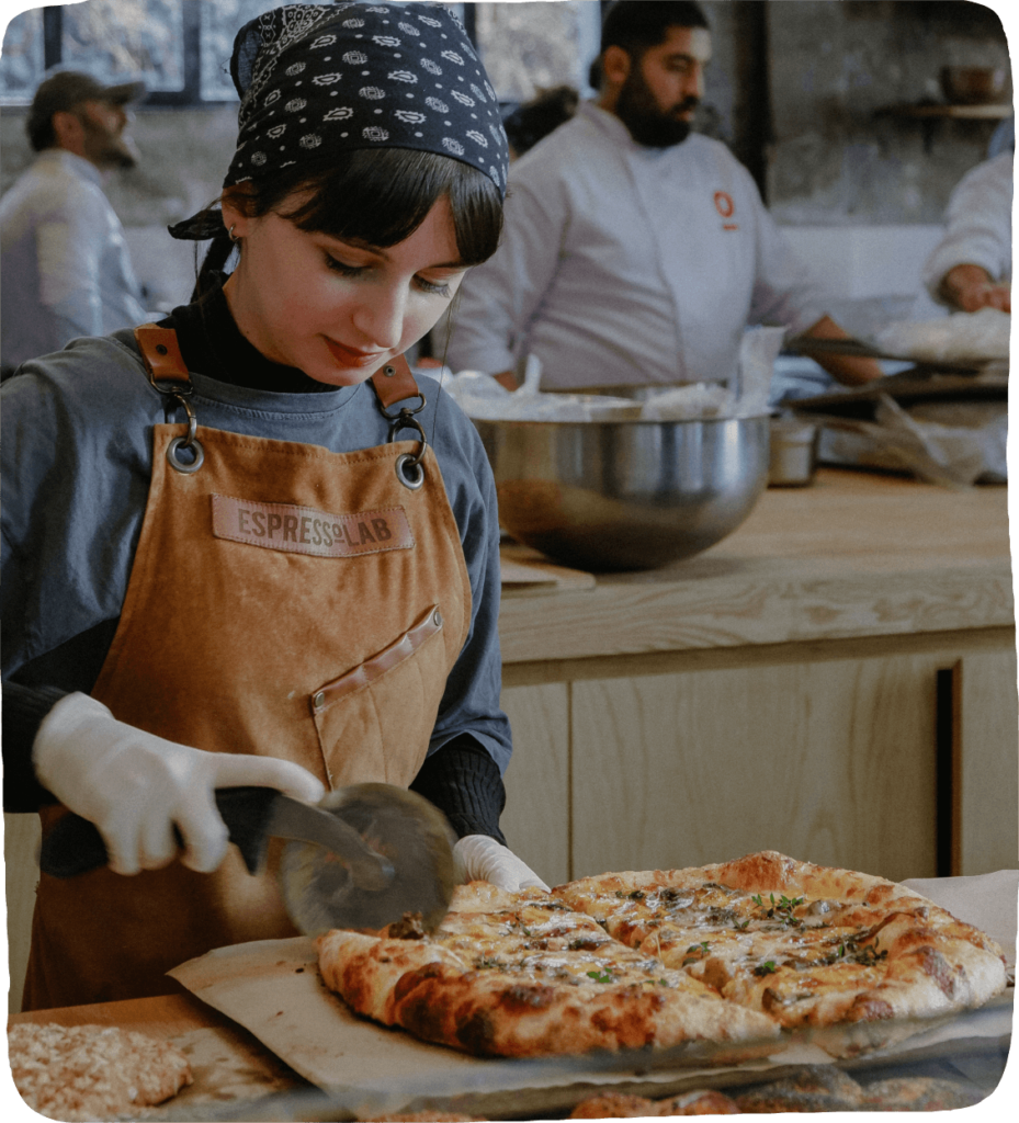 Image of a worker cutting pizza in a pizza restaurant to inspire these fun activities for kids to play. 