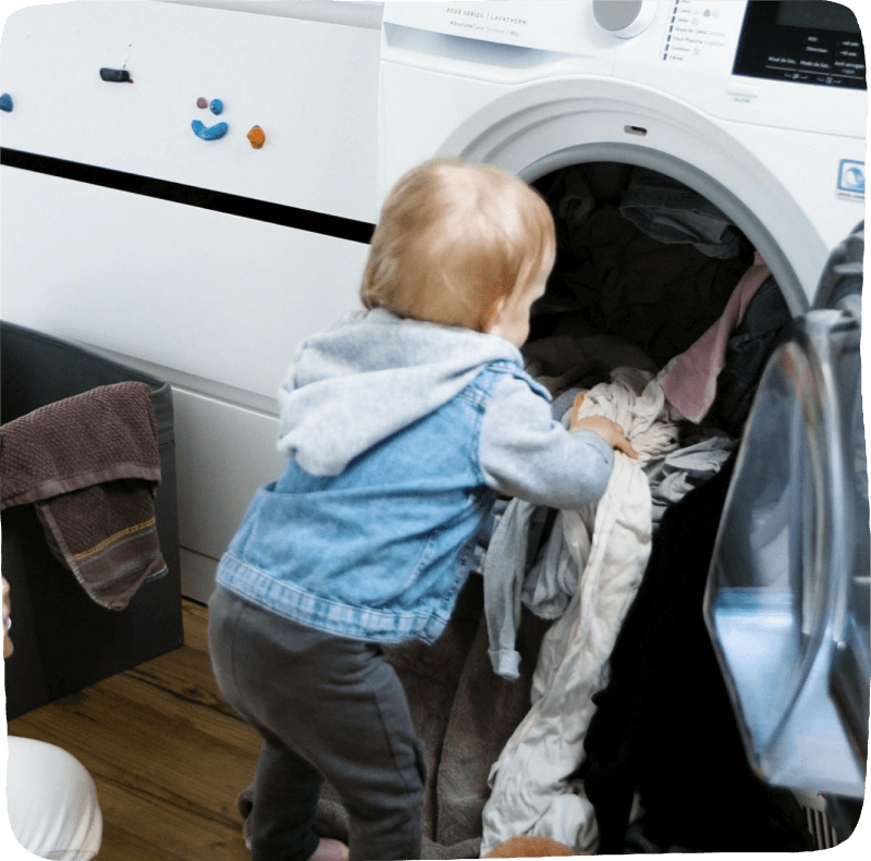 child pulling clothes out of the dryer for kids learning activities chores